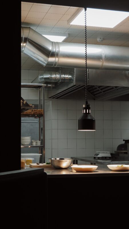 Implantation de cuisine professionnelle en îlot avec équipement inox accessible des deux côtés