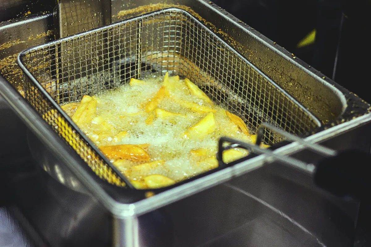 Panier de frites en cuisson dans une friteuse professionnelle