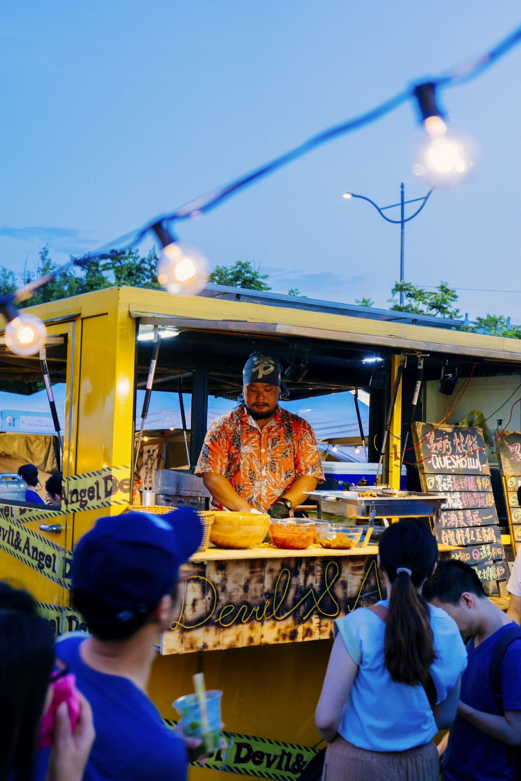 Food truck jaune éclairé par une guirlande lumineuse en soirée