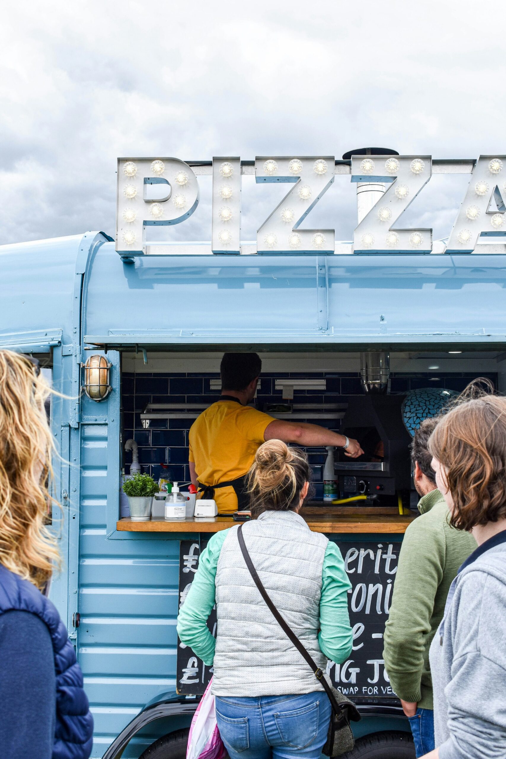 Clients devant un food truck à pizzas