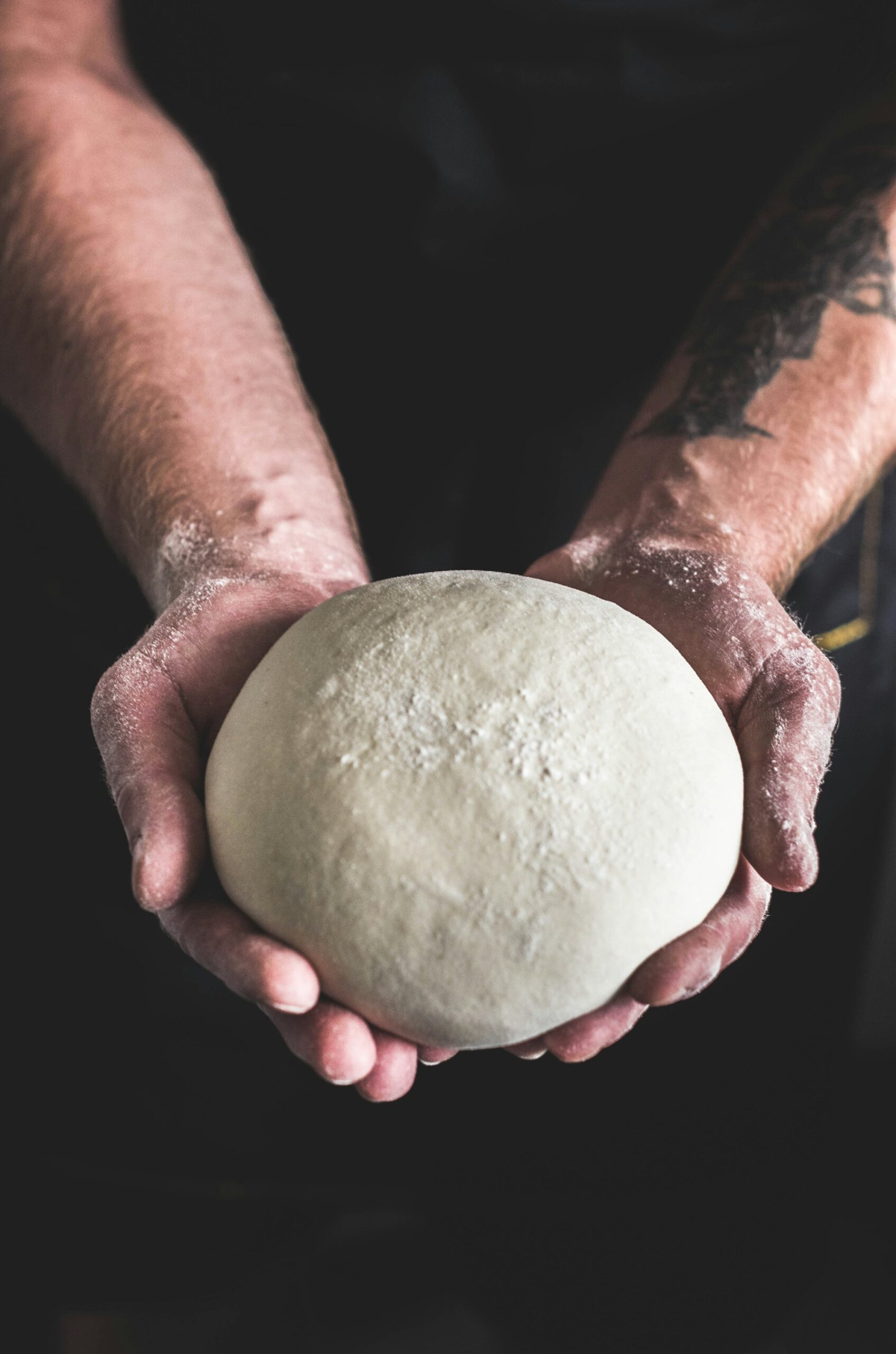 Pâton de pizza tenu à deux mains
